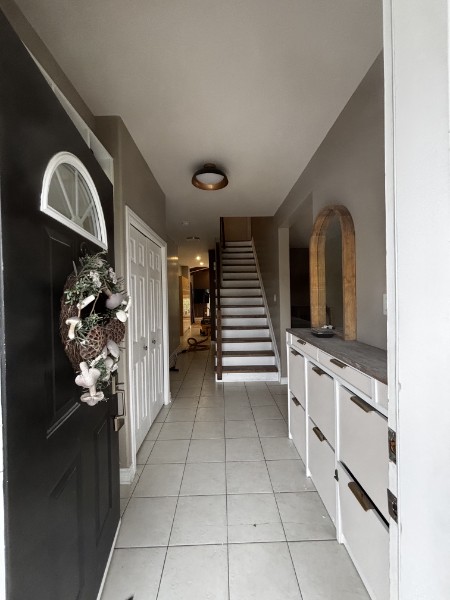 Entryway with tile floor, staircase and custom built-in storage